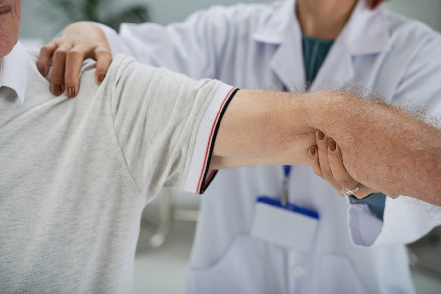 Rheumatologist examining a patient's shoulder and arm to assess joint pain and mobility during a clinical consultation.