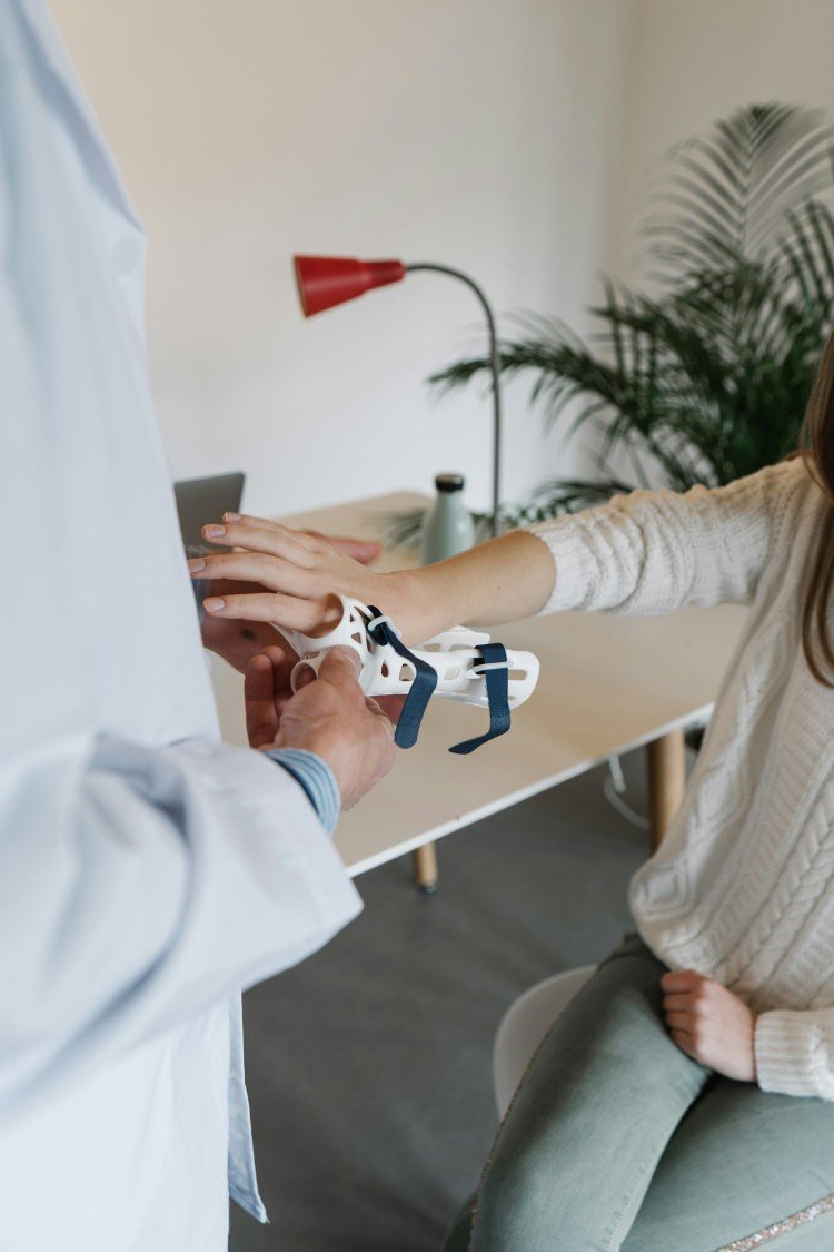 Doctor examining a patient's wrist with a hand brace during a rheumatology consultation for joint pain.